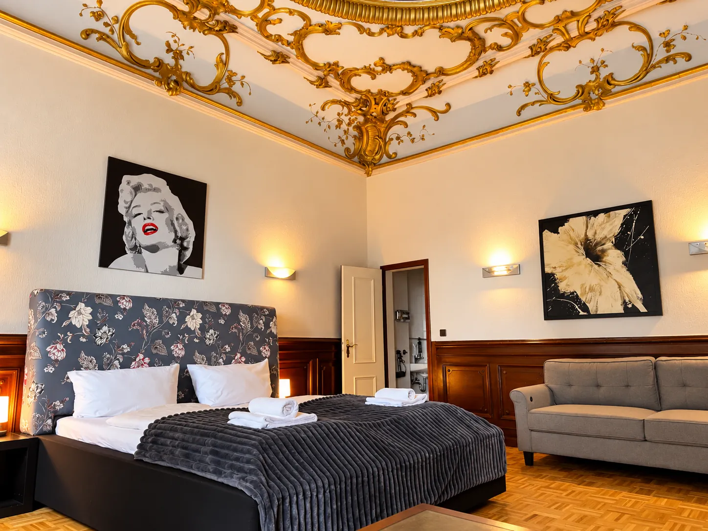 Double bed under the ornate ceiling, with sofa