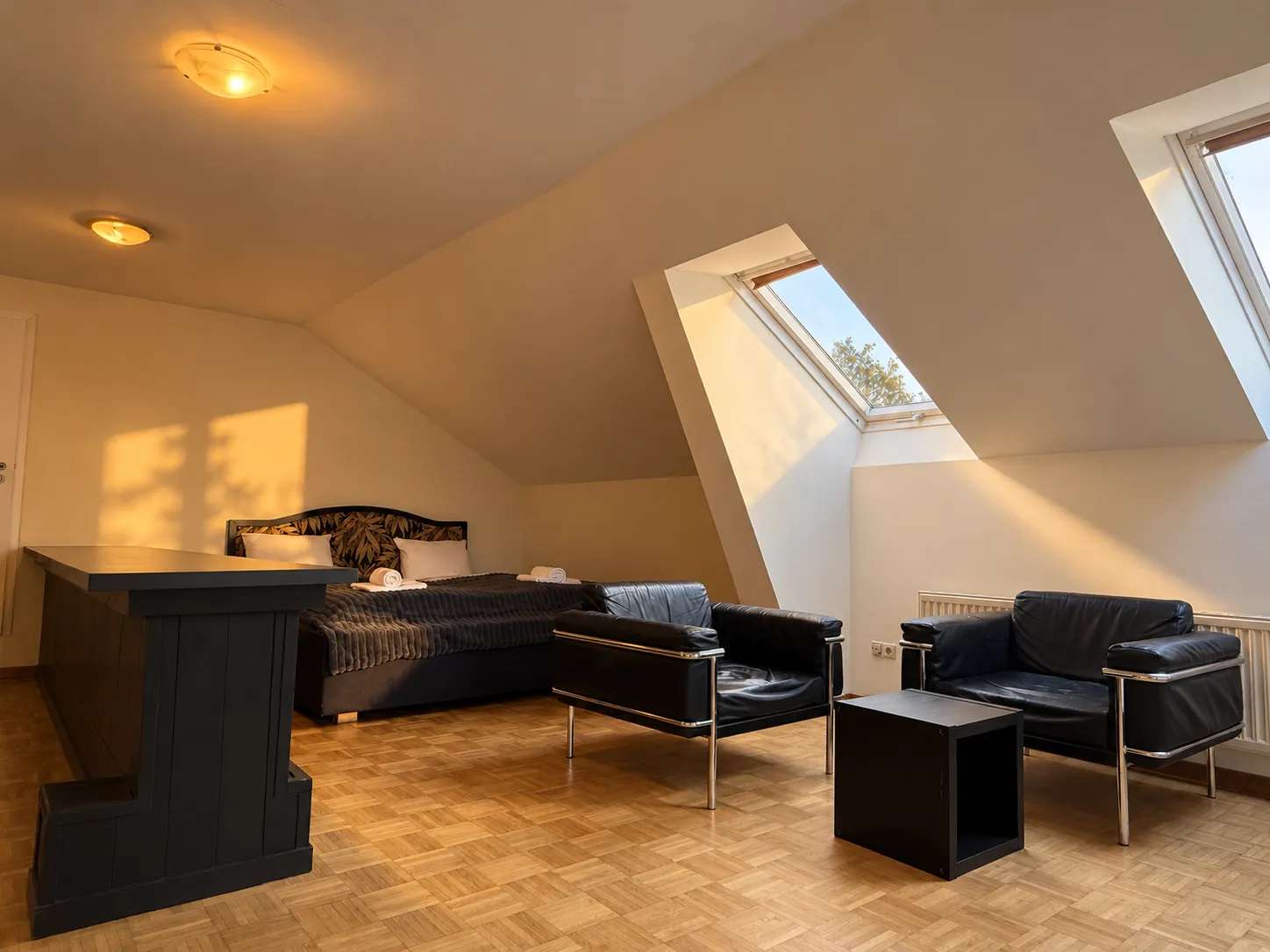 Großes Dachzimmer mit Bett und Ledersesseln