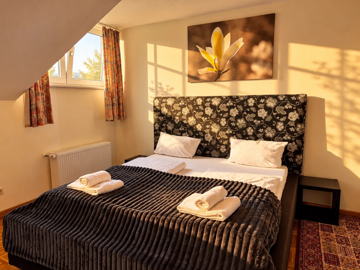 Double bed with floral headboard in a sunny attic room