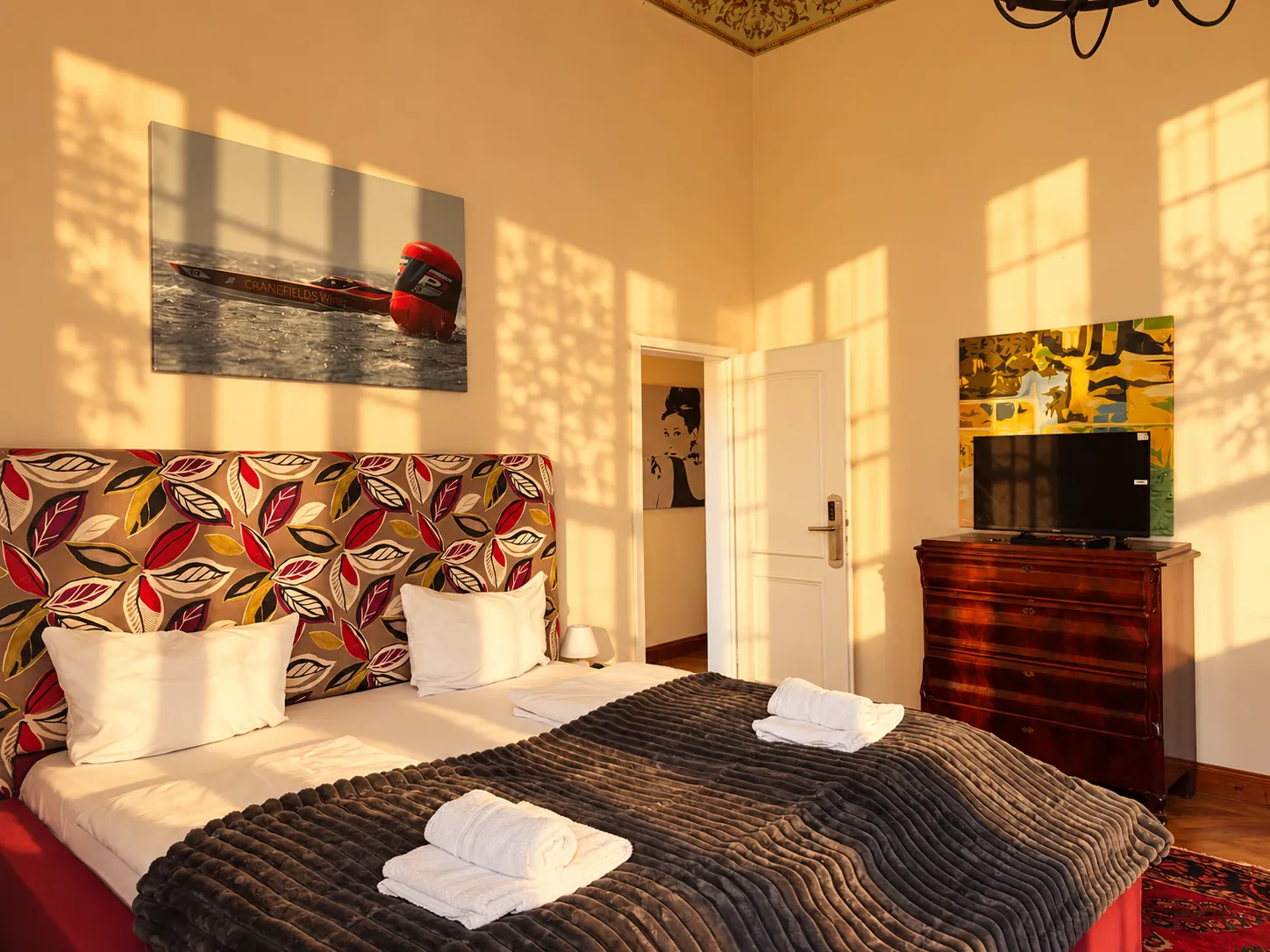 Double bed with patterned headboard in a high-ceilinged room